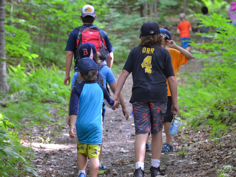 Teamwork makes the dream work. Here's an older camper giving some support to a younger camper while on a hike during Mud City Adventures day camp in Stowe Vermont.