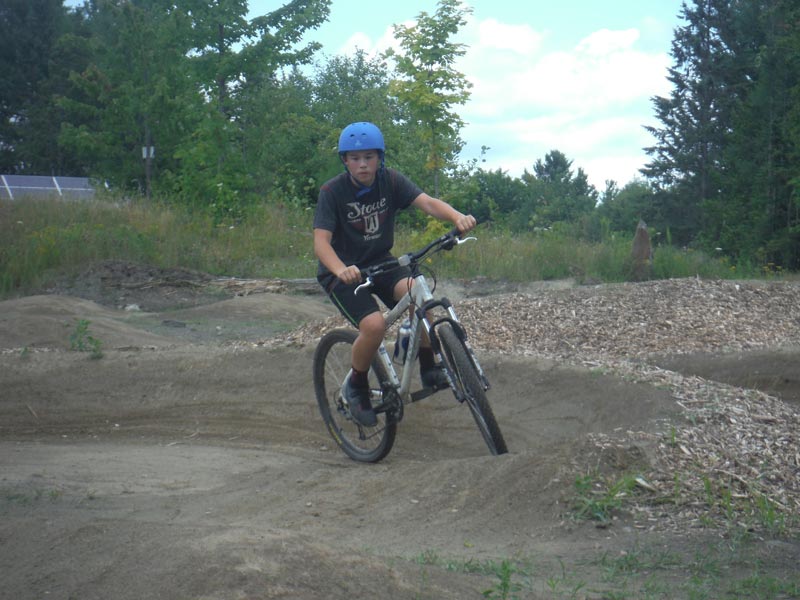 Here's one happy camper coming out of a sweet turn in the MTB / BMX pump track, where we give kids beginner mountain bike lessons before heading into the woods.