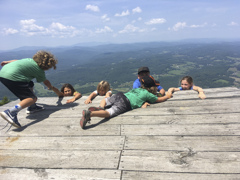 Here is one of the Mud City Summer Camp counselors braiding a campers hair while taking a break from kayaking on a warm summer day in Waterbury, Vermont.