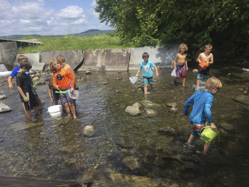 Here is one of the Mud City Summer Camp counselors braiding a campers hair while taking a break from kayaking on a warm summer day in Waterbury, Vermont.